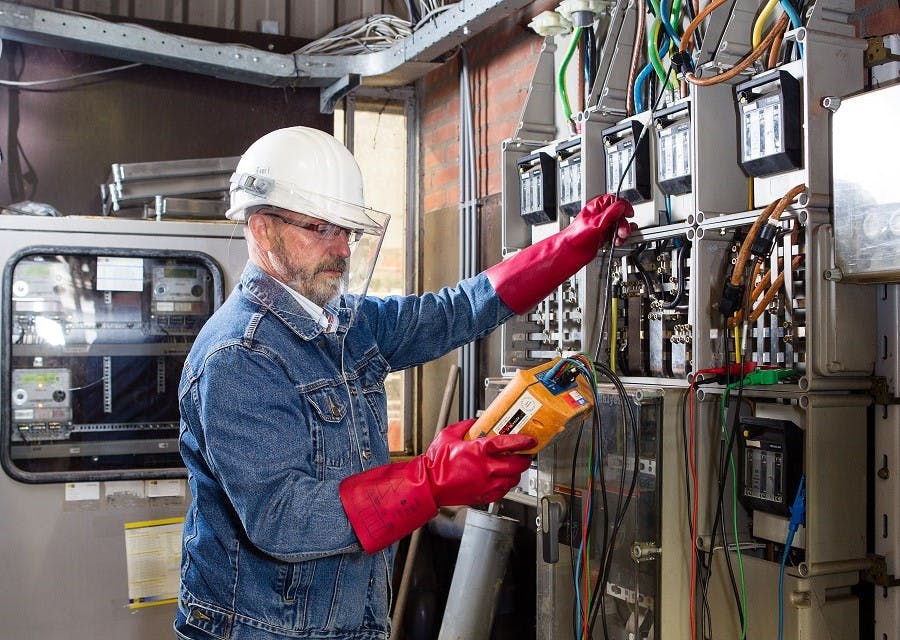 Man met beschermende handschoenen en helm op doet een elektrakeuring