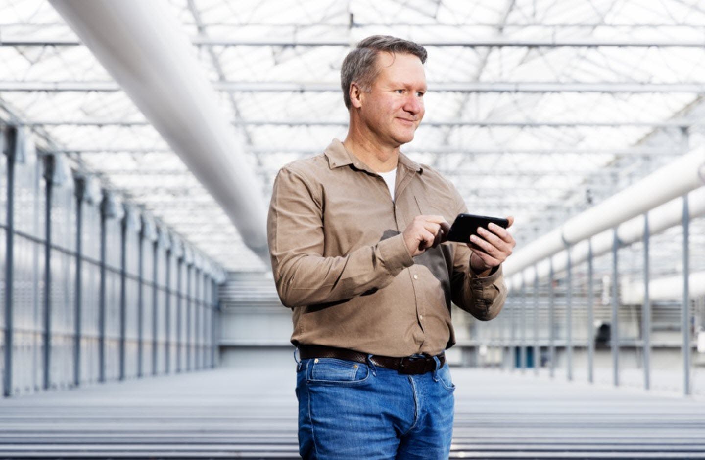 Tulpenbroeier Bas Karsten staat in zijn bedrijf met zijn mobiele telefoon in de hand.