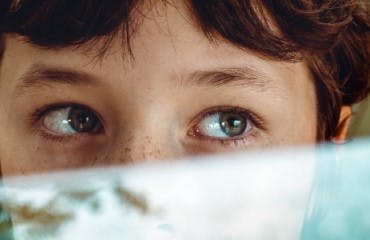 Kind op de achterbank in een auto dat uit het raam kijkt