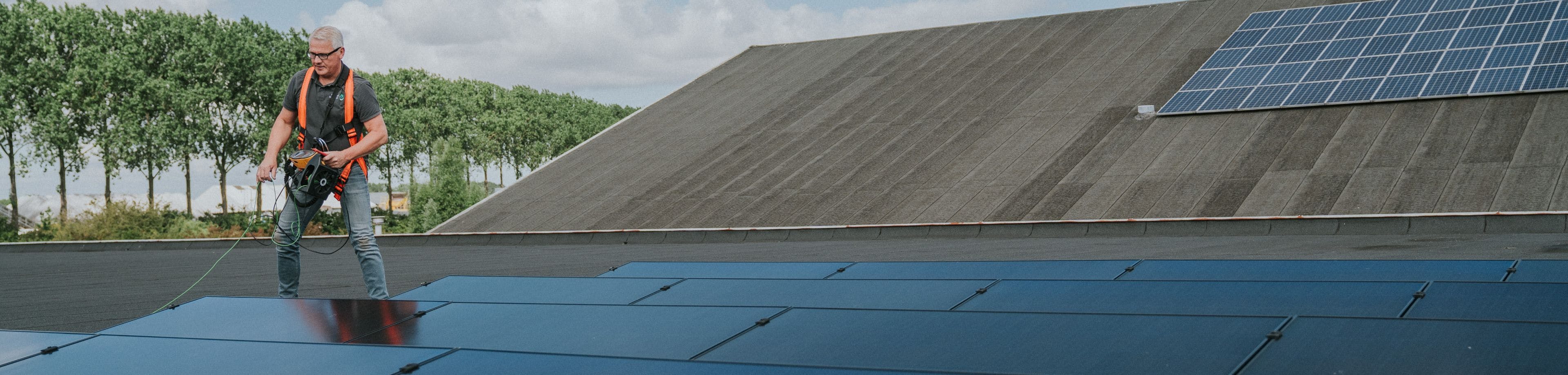 De inspecteur staat op het dak van een bedrijfsgebouw en keurt de zonnepaneleninstallatie.