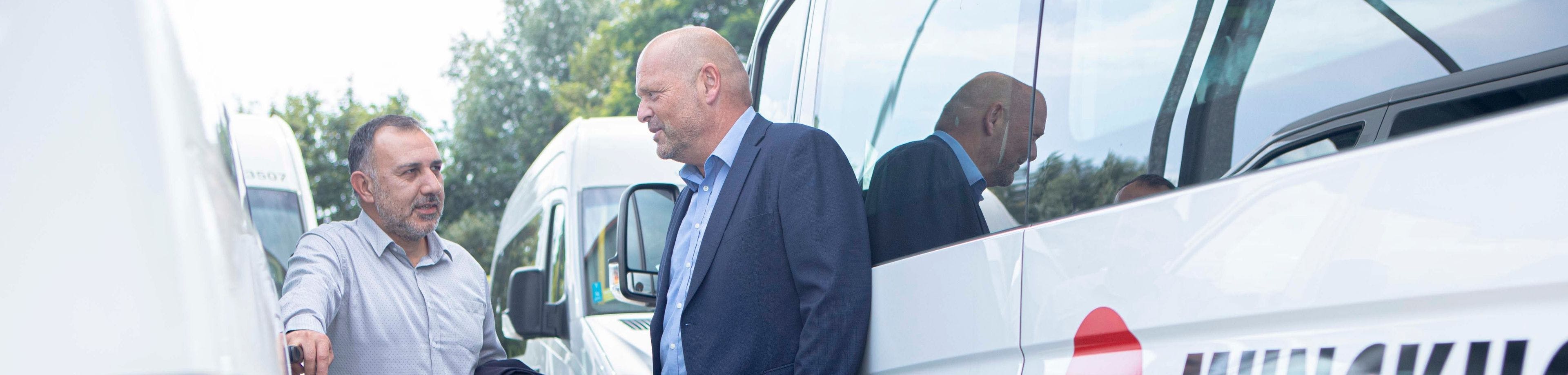 2 mannen in overleg staand tegen taxi van Munckhof