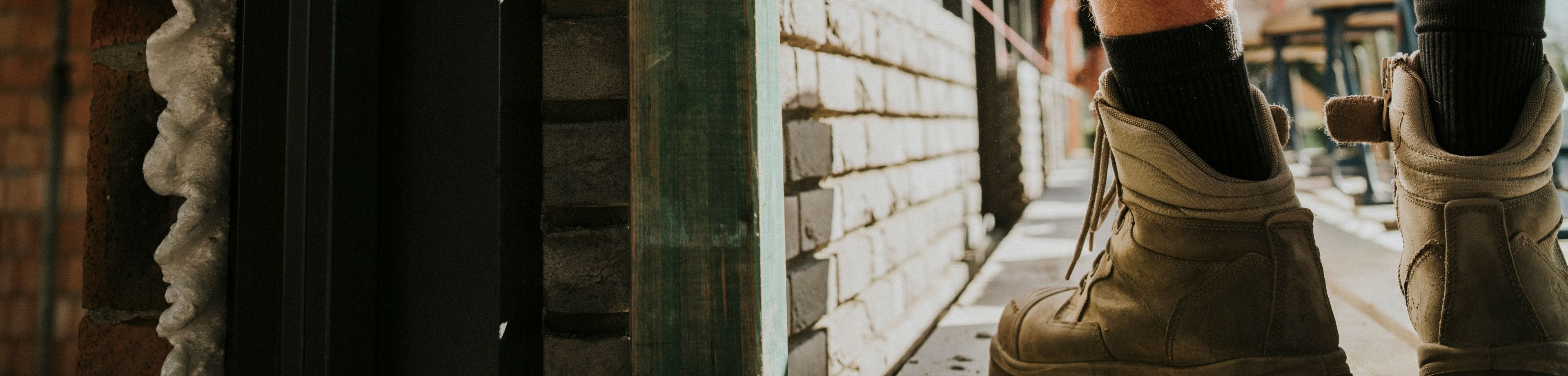 Schoenen van een bouwvakker naast een muurtje dat hij bouwt