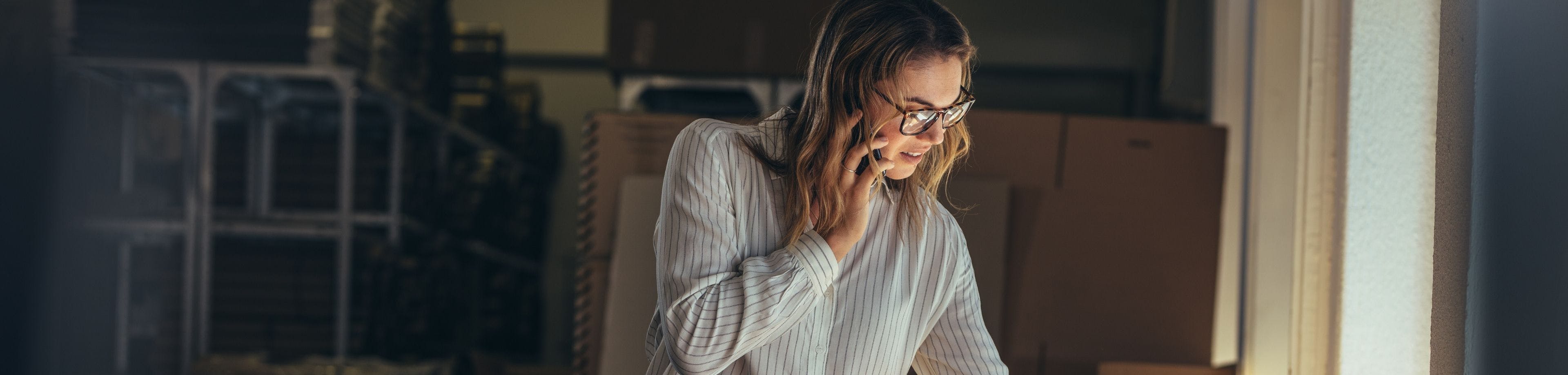 Vrouw met bril en gestreepte blouse belt met mobiele telefoon