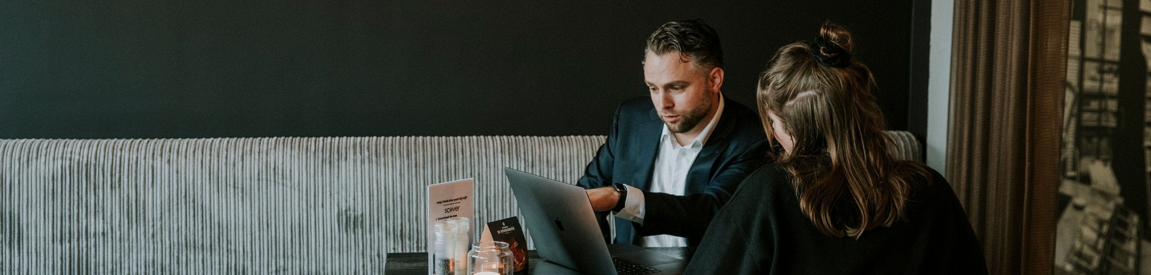 Man en vrouw in overleg achter laptop