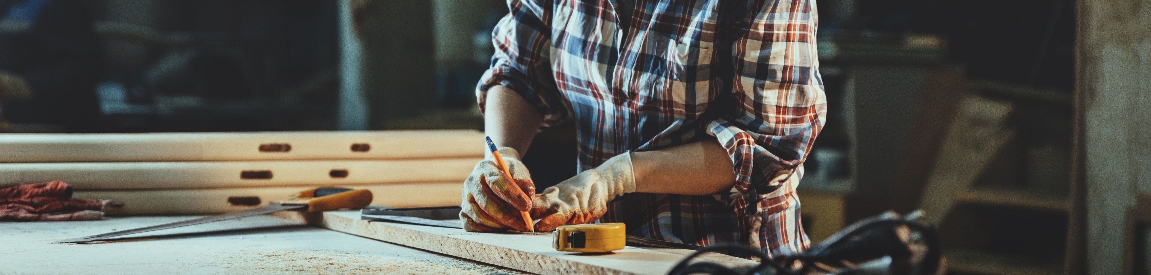 ZZP'er meet de lengte van een plank om te bewerken in de werkplaats