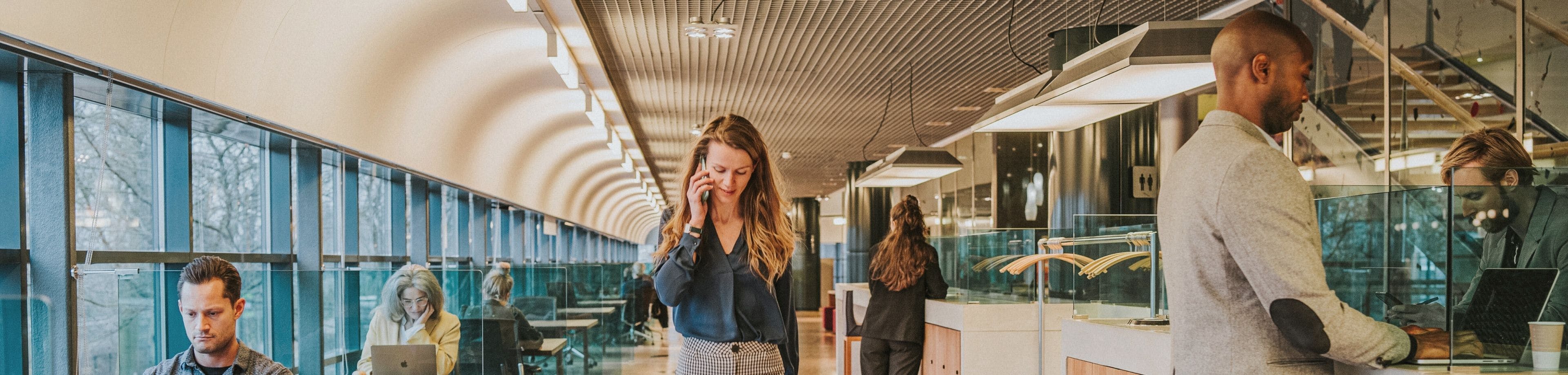Vrouw loopt bellend in een kantoor. Grenzen tussen werk en privé vervagen steeds meer.