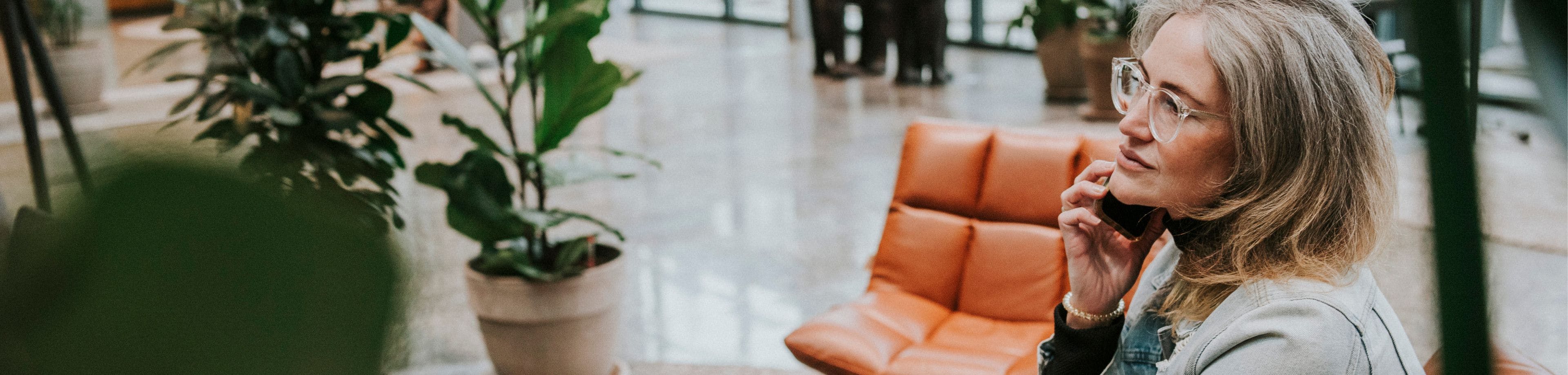 Vrouw zit met de telefoon aan haar oor in een kantoorhal.