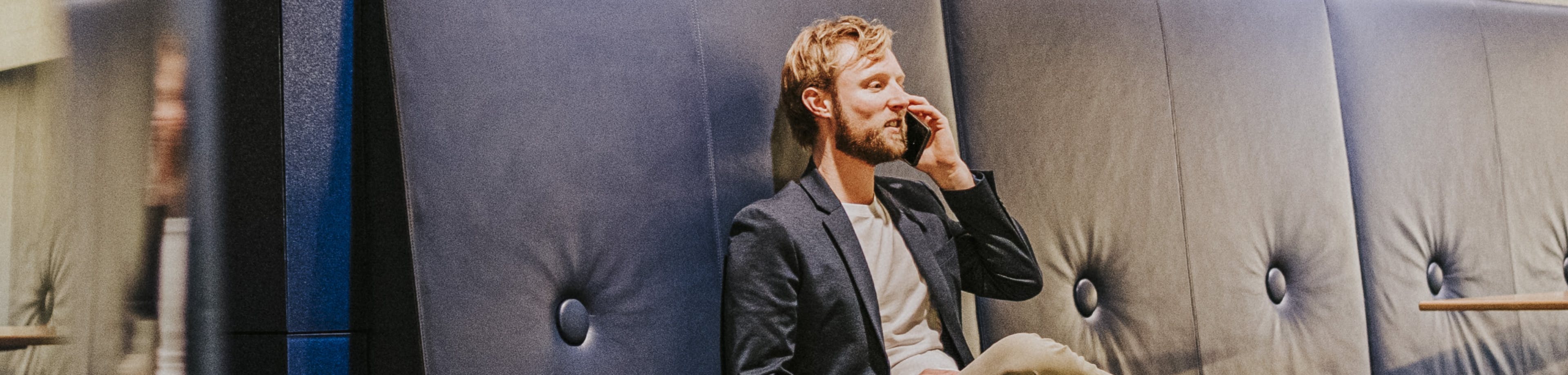 Een man zit bellend op een bankje