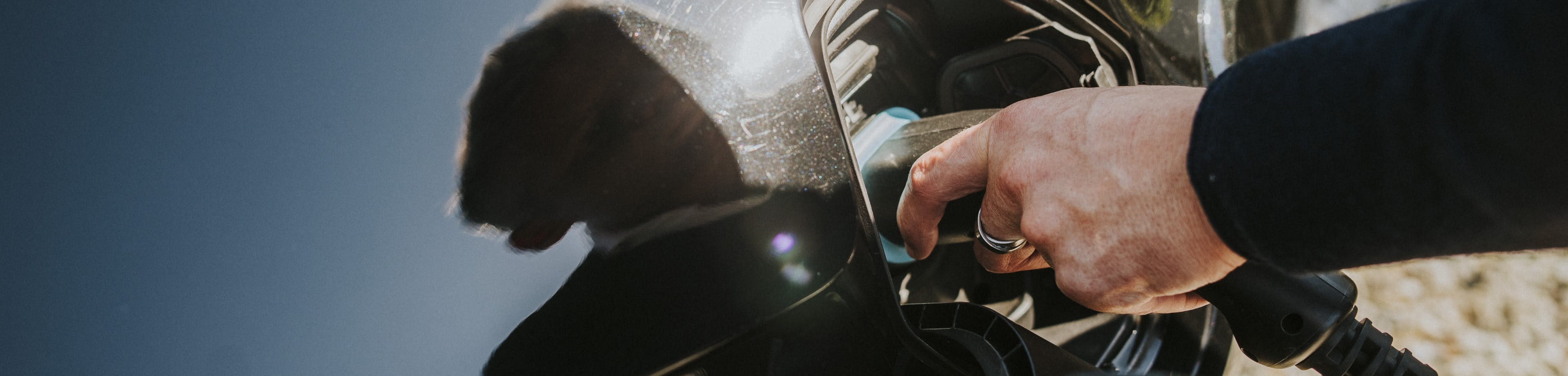 Iemand steekt de stekker in een elektrische auto om deze op te laden