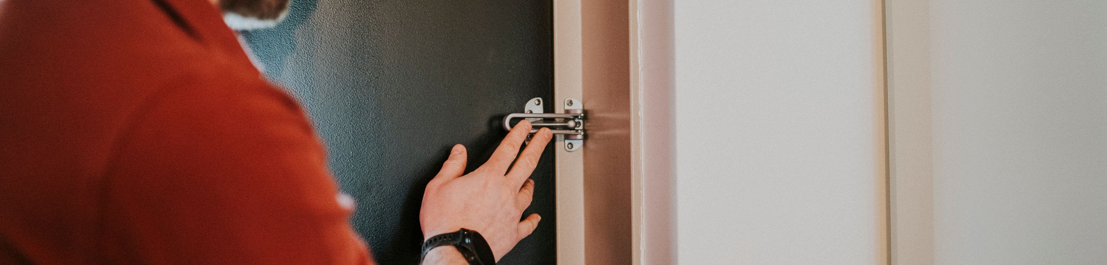 Man heeft een veiligheidsslot op zijn voordeur, naast het gewone slot