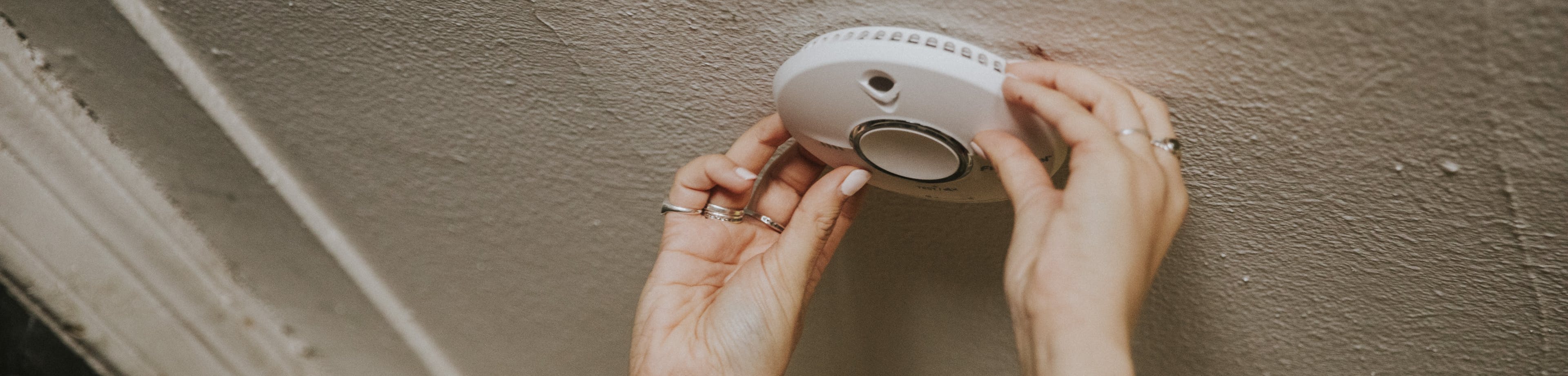 Iemand bevestigt een rookmelder aan het plafond