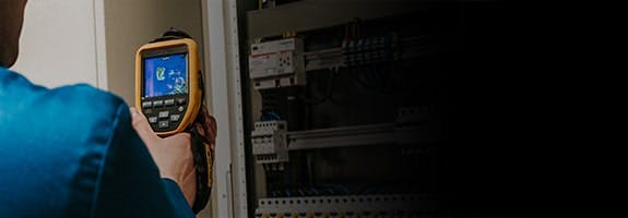 Een man gebruikt een apparaat waarmee je de elektrische installatie kan doormeten.