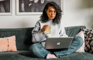 Vrouw zit op de bank met haar laptop op schoot