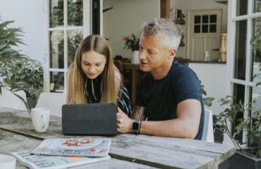 Vader en dochter lezen het Interpolis magazine achter de laptop.