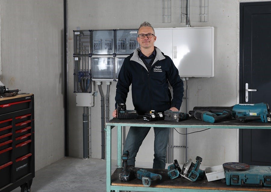 Emile van Nieuwenhoven staat aan een werktafel met daarop divers accu-gereedschap. - Foto: Natasja Beverloo