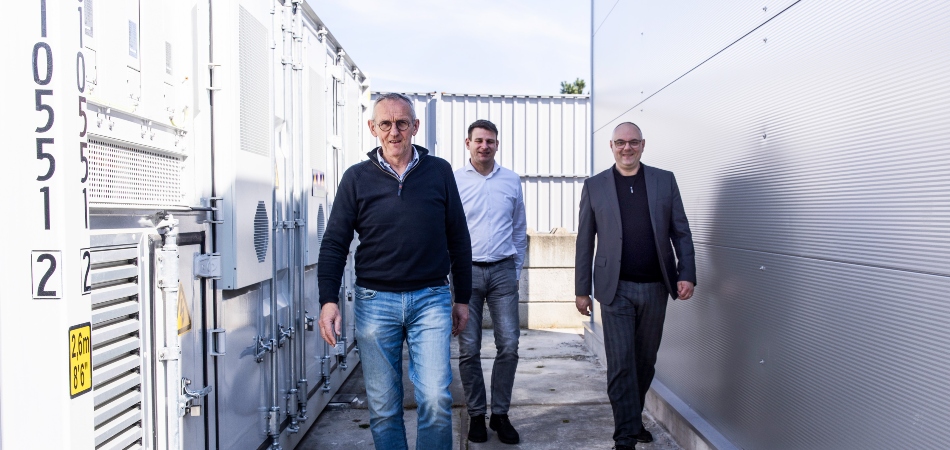 3 mannen lopen tussen de containers op een buitenlocatie voor energieopslag.