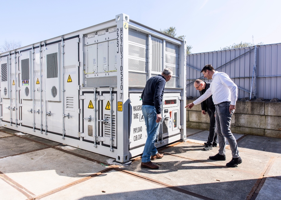 3 mannen inspecteren een container voor energieopslag op een buitenterrein.