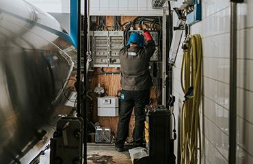 Man staat in meterkast en repareert iets