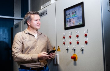 Een man staat naar een elektronische regelunit.