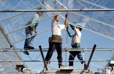 3 mannen zijn bezig het dak van een kas te herstellen