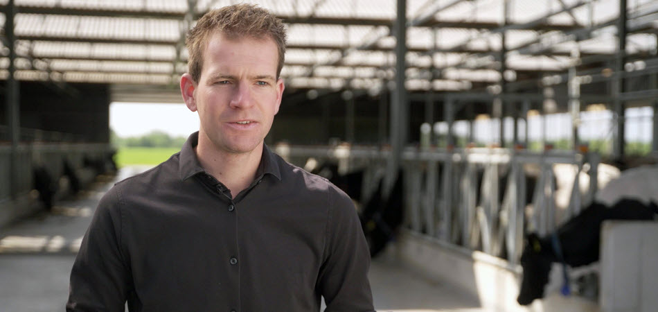 Melkveehouder Bas staat in de stal bij de koeien.