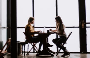 Twee vrouwen die aan een tafeltje zitten en in gesprek zijn