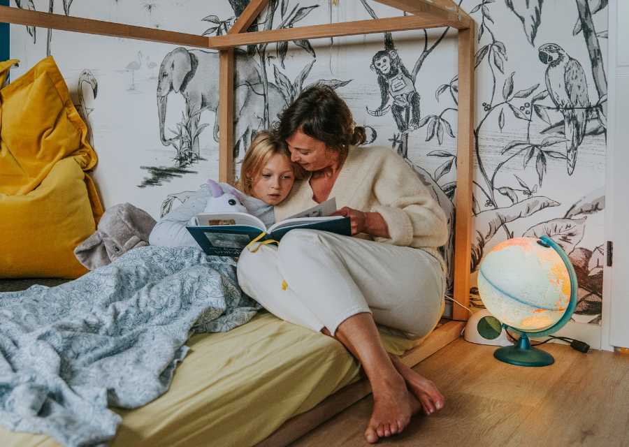 Moeder en kind lezen samen een boek op bed.