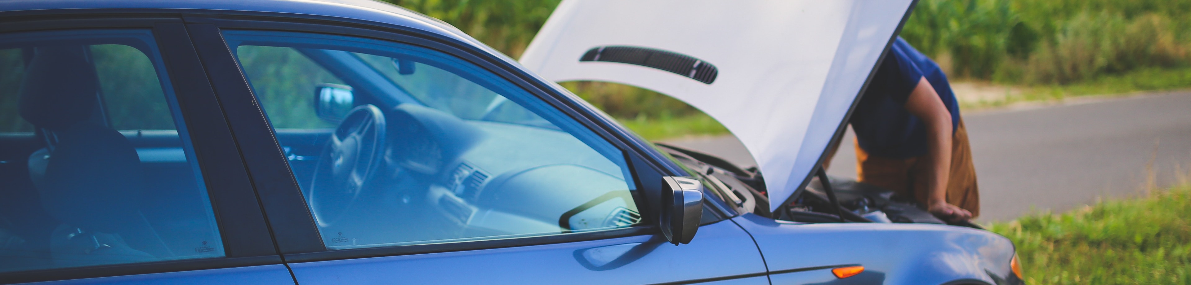 Iemand die onder de motorkap van een auto kijkt