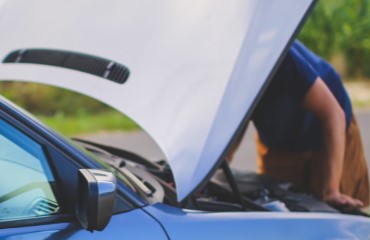 Man die onder de motorkap van zijn auto kijkt