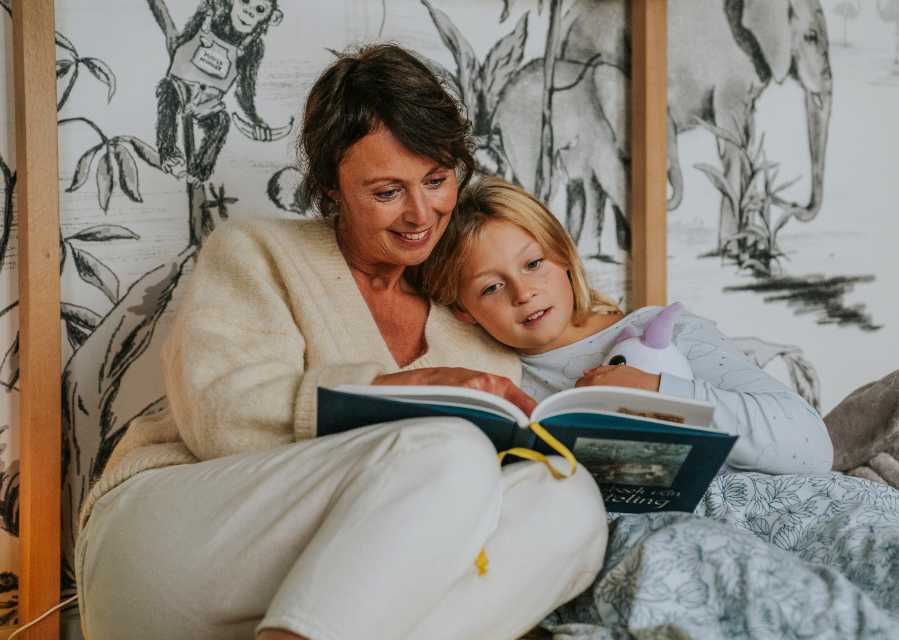Moeder leest dochter voor in bed.