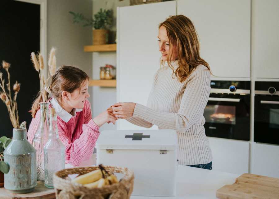 Een vrouw plakt een pleister op de vinger van haar dochter.