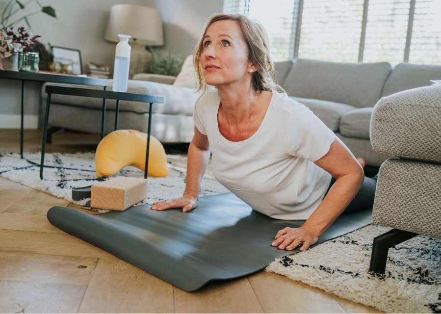 Een vrouw voert een yoga-oefening uit in de woonkamer.
