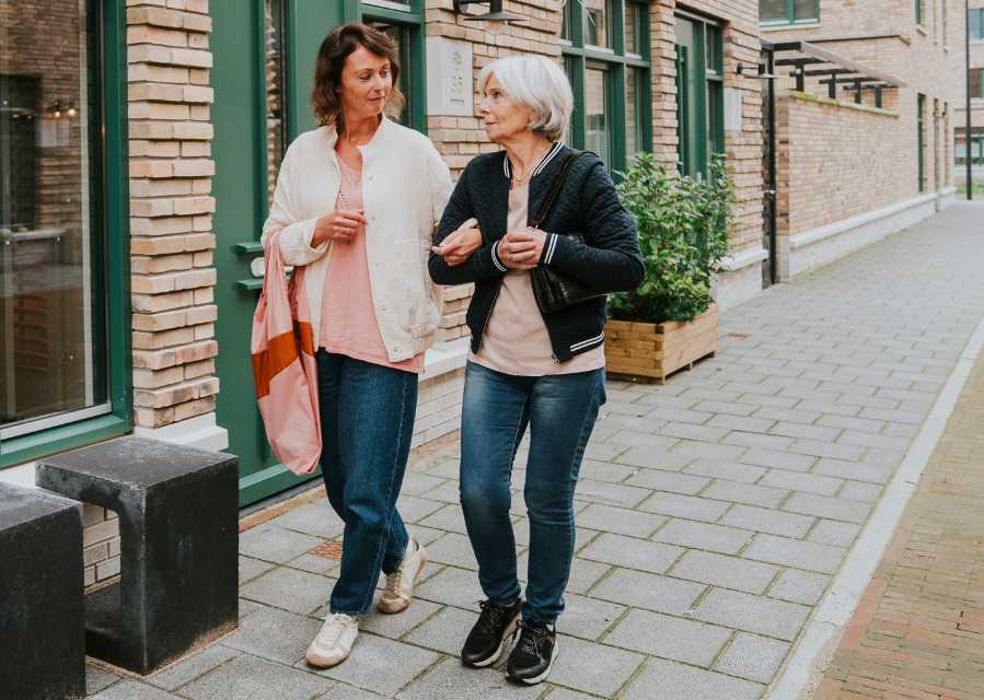 Vrouw loop met haar moeder over straat. 