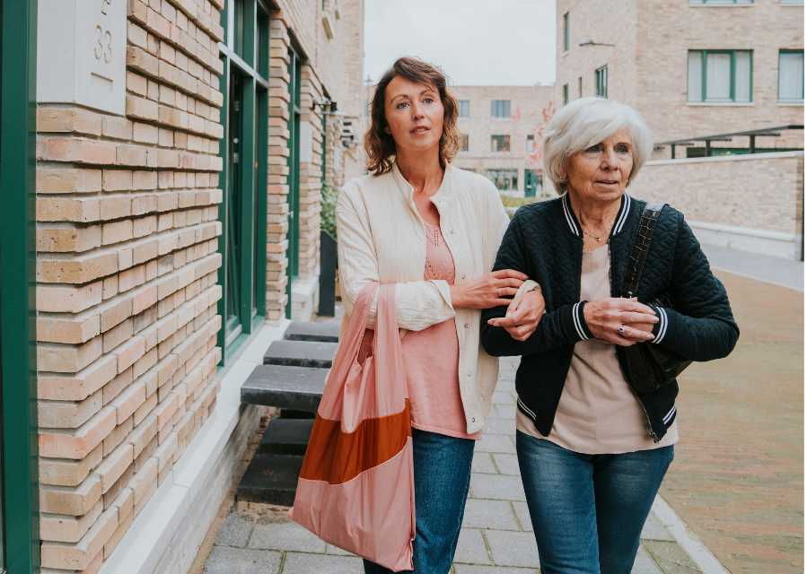 Vrouw en moeder lopen over straat door een woonwijk.