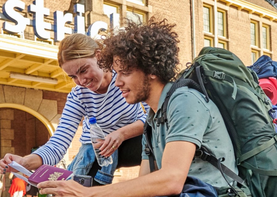 Man en vrouw die bij het Centraal Station van Maastricht op een kaart kijken