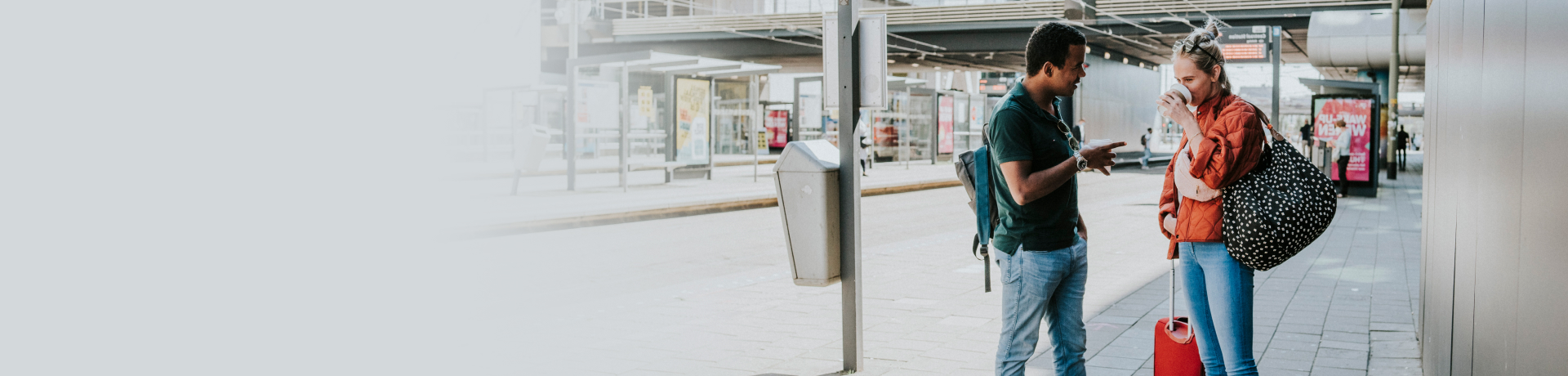 Een man en vrouw staan samen met hun bagage bij de bushalte.