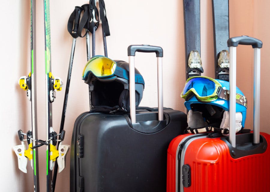Koffers met skihelmen op en ski's ernaast