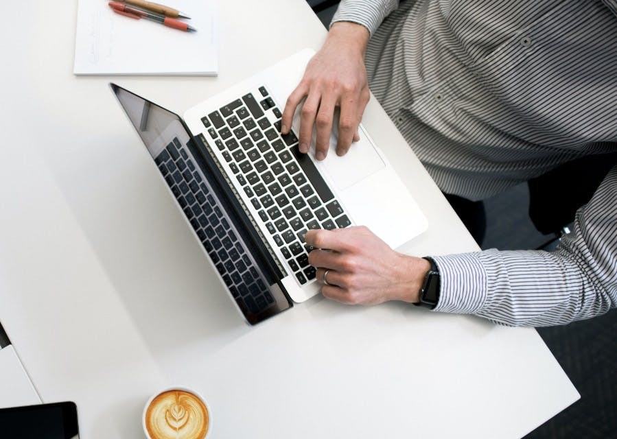 Bovenaanzicht van toetsenbord van een laptop en kopje cappuccino