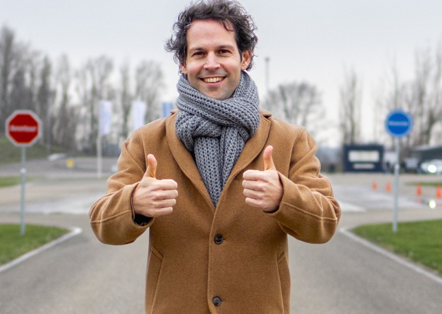 Victor Mids die op een racecircuit staat en zijn duimen opsteekt