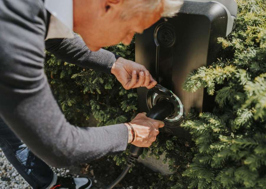 Man stopt de laadkabel van zijn elektrische auto in de oplader | Interpolis verzekeringen