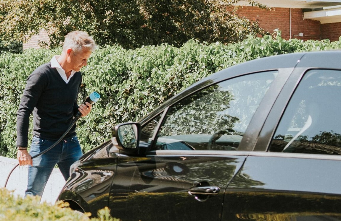 Man die de oplader van een elektrische auto aansluit