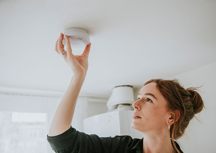Vrouw hangt een rookmelder op.