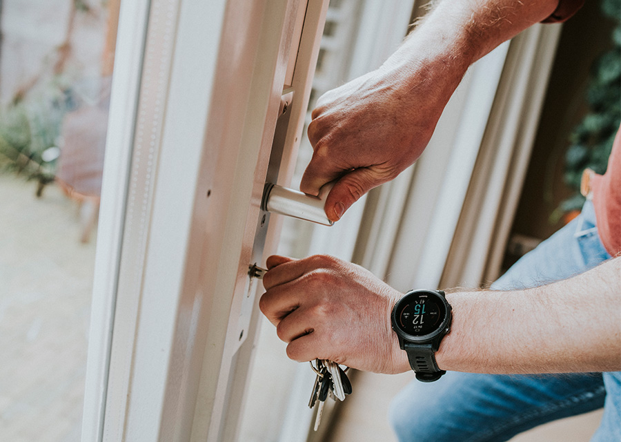 Man draait het slot van zijn tuindeur dicht.