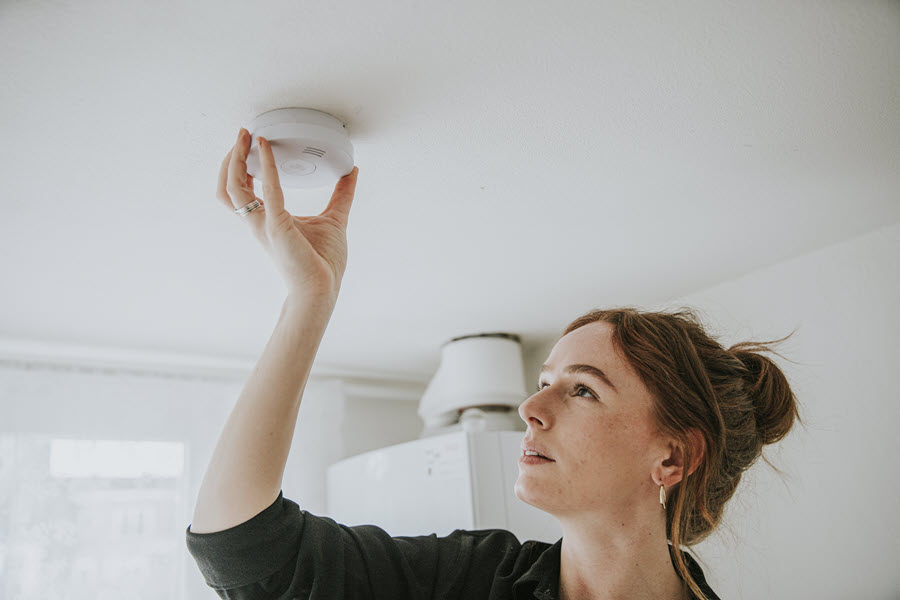 Een vrouw hangt in 3 simpele stappen een rookmelder aan het plafond.