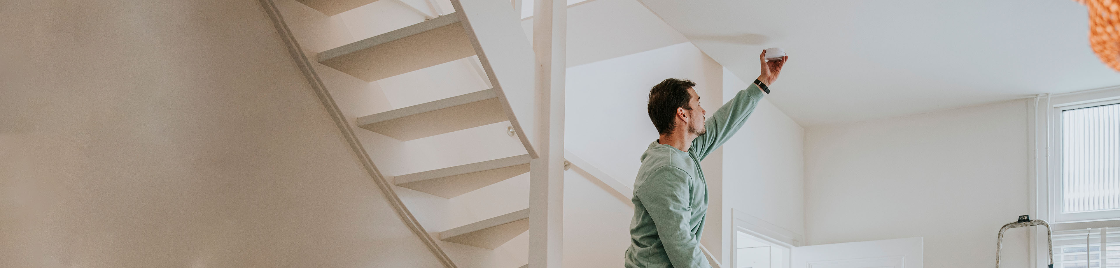 Man hangt een rookmelder op.