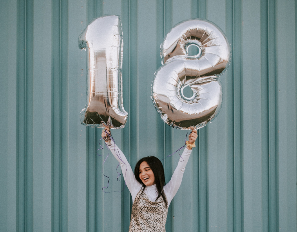 Meisje dat twee ballonnen in de vorm van een 1 en een 8 in de lucht houdt