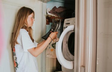 Jonge vrouw staat bij de wasmachine