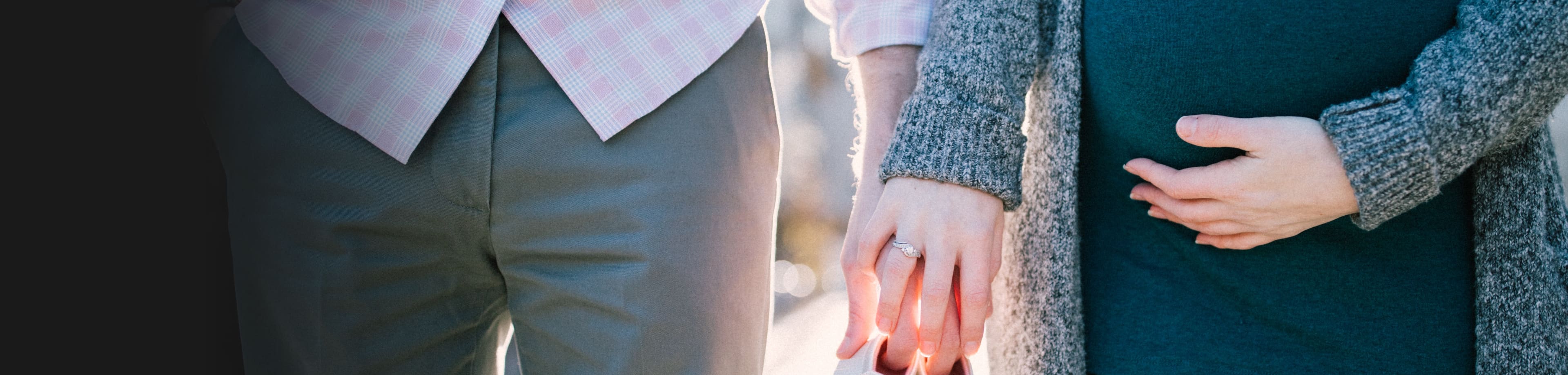 Twee mensen die naast elkaar lopen en samen babyschoentjes vasthouden