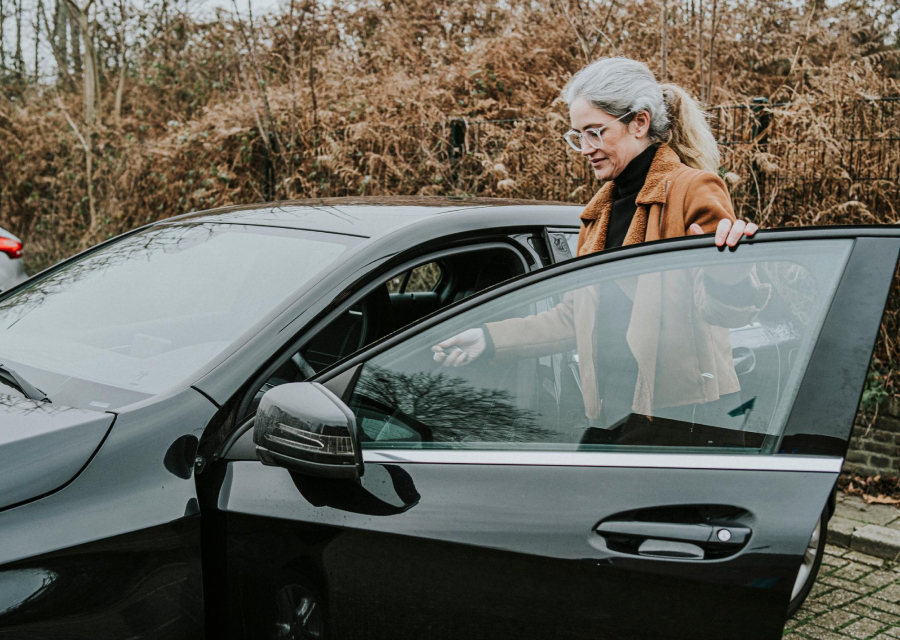 Een vrouw stapt in een auto.
