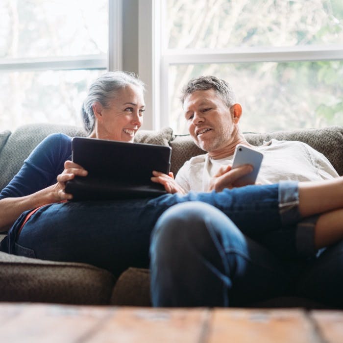 Man en vrouw die op de bank zitten en samen op een tablet kijken